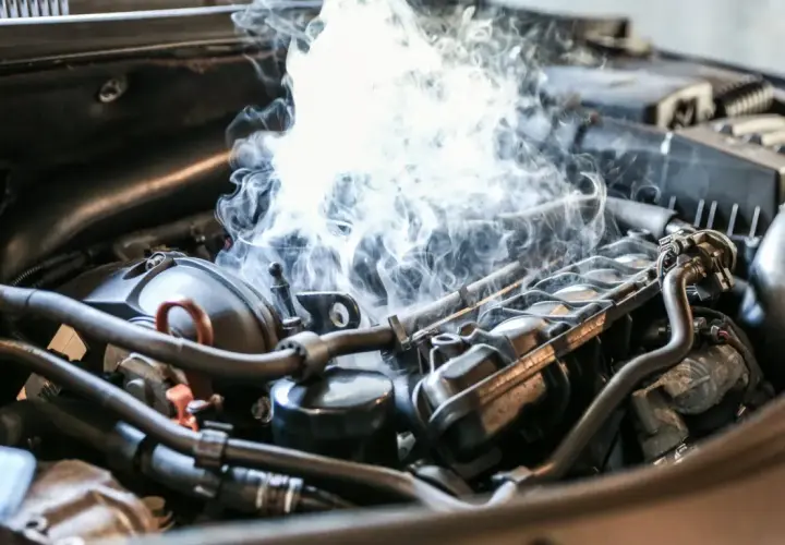 Fumée épaisse s'échappant du compartiment moteur d'une voiture essence, signe d'une cause surchauffe moteur essence.