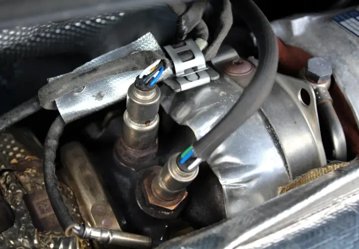 Sonde lambda défectueuse : câblage visible, connecteurs et partie métallique rouillée. Un symptôme de problème moteur.