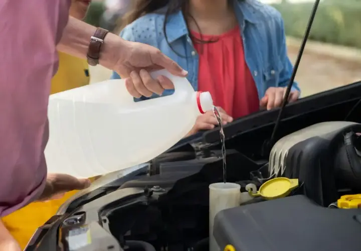 Main d'homme versant du liquide dans le réservoir, vérifiant le niveau liquide de frein.