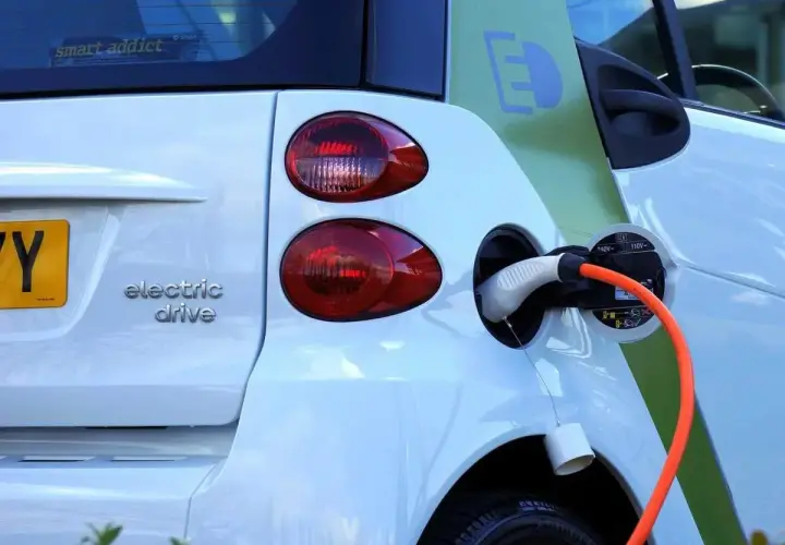 Une voiture électrique blanche est branchée. La question est : peut-on laisser charger une batterie de voiture toute la nuit ?