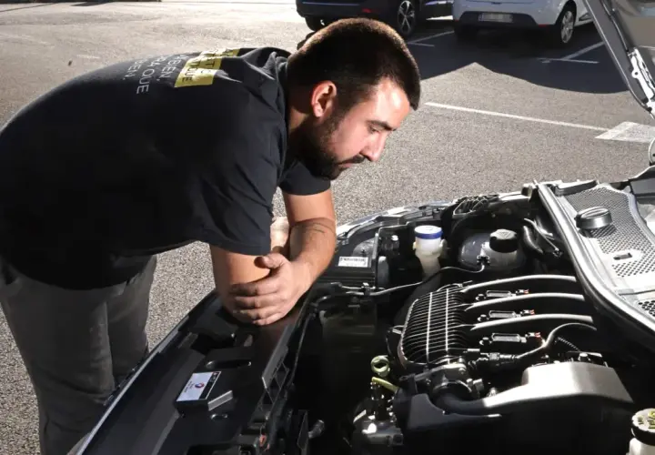 Un mécanicien examine un moteur de voiture, soucieux du risque de casse moteur.