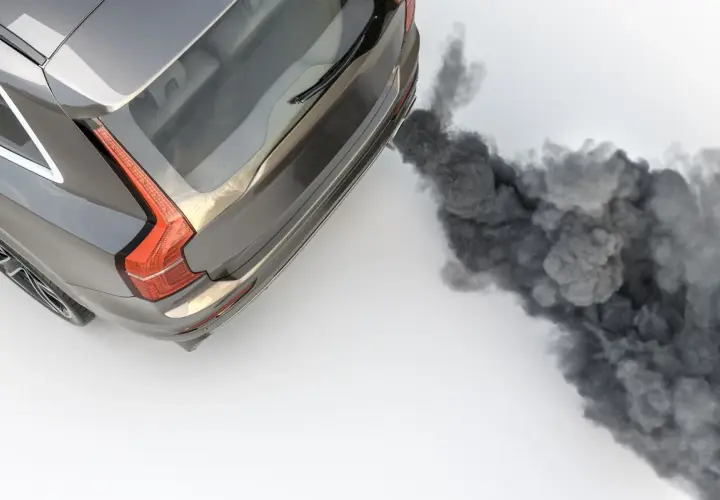 Vue aérienne d'un SUV gris émettant une épaisse fumée noire d'échappement, symbolisant la pollution.