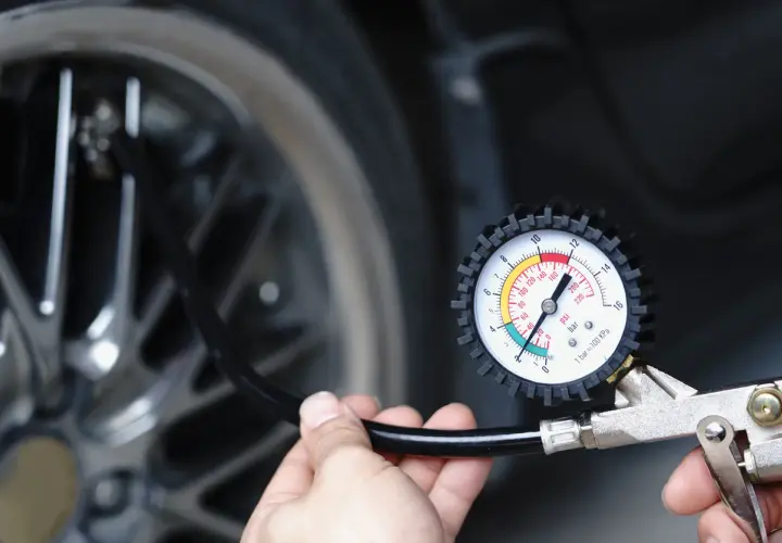Main tenant vérifie la pression du pneu de voiture avec un manomètre. Il est prêt à gonfler le pneu.