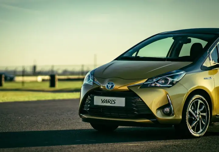 Toyota Yaris hybride dorée sur route asphaltée, prête pour sa vidange.