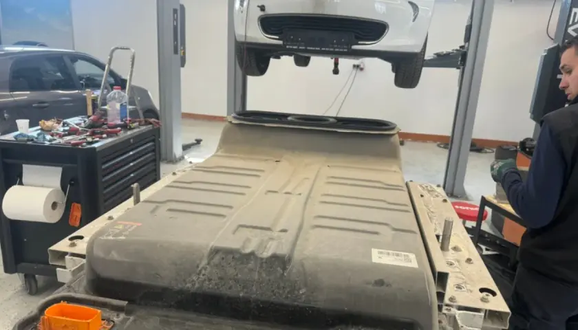 Un mécanicien travaille sur une batterie de voiture électrique, peut-être pour un changement de batterie chez Renault.