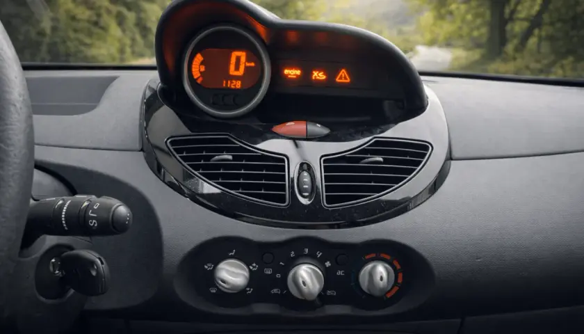 Tableau de bord d'une Twingo 2, prêt pour la vidange. Le compteur affiche 0 km/h, avec des voyants moteur et d'alerte allumés.