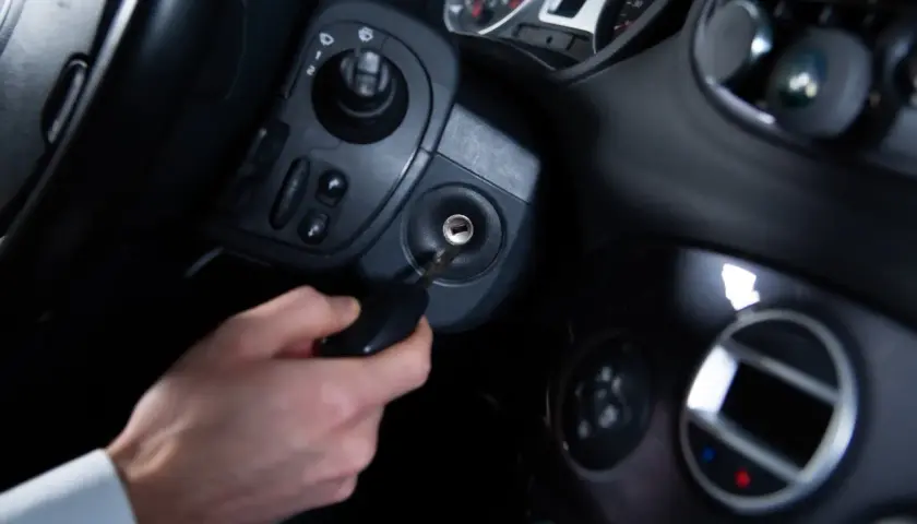 Main d'homme insérant une clé dans le Neiman d'une voiture. Le prix du changement de Neiman est une préoccupation courante.
