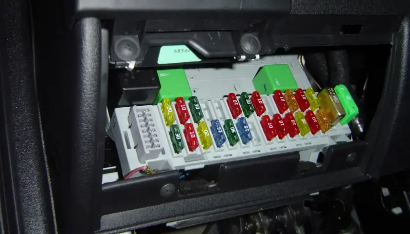 Boîte de fusibles de voiture avec des fusibles colorés de différentes ampérages. Un fusible de 20A est visible.
