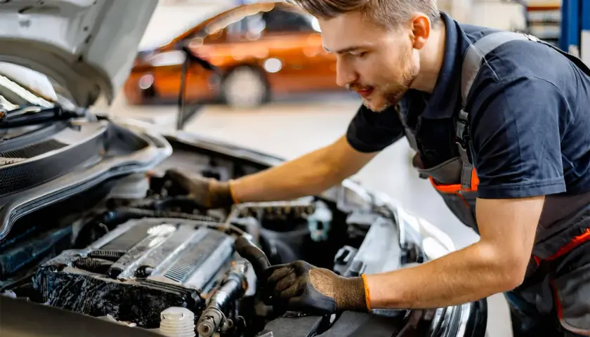 Mécanicien travaillant sur le moteur d'une voiture. Il explique comment changer une batterie de voiture sans perdre les données.