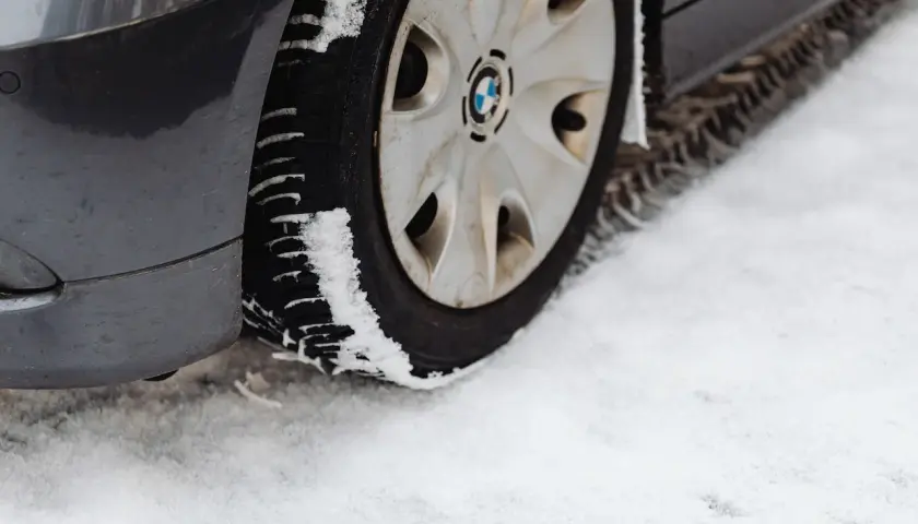 Pneu de voiture sur la neige. La neige s'accumule sur le pneu, illustrant pourquoi les pneus 4 saisons sont à éviter en conditions hivernales extrêmes.