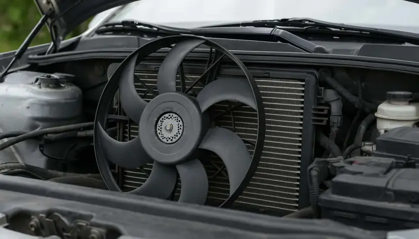 Le ventilateur de voiture est visible devant le radiateur, prêt à refroidir le moteur froid.