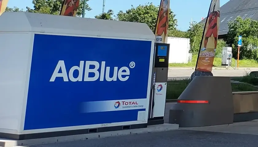 Station-service Total avec une pompe AdBlue à la vue. Des drapeaux aux couleurs nationales flottent au-dessus.