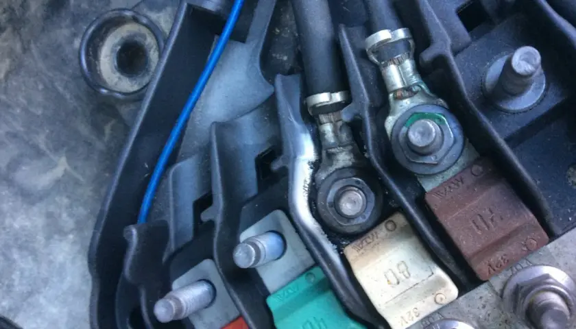 Boîtier de fusibles d'une Peugeot 207, incluant le fusible direction assistée. Connexions et câbles visibles.