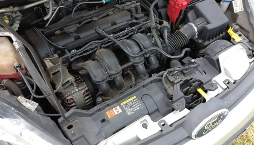 Moteur de Ford Fiesta essence. Le démarreur est caché sous le collecteur d'admission, près de l'alternateur.