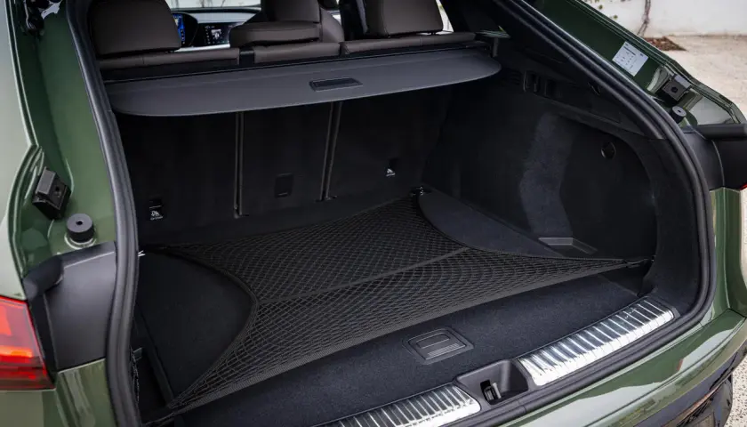 Coffre d'Audi Q5 vert, avec filet de rangement. L'emplacement de la batterie est discret sous le plancher.