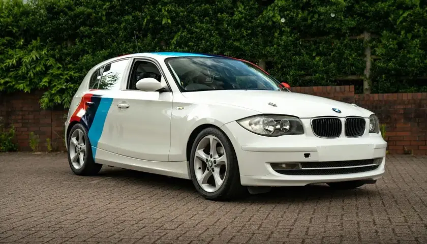 BMW blanc avec bandes tricolores sur le flanc, prêt pour son entretien.
