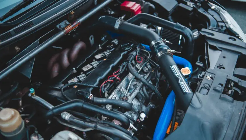 Moteur de voiture avec durites bleues et noires. Un symptôme capteur pression admission HS peut être lié à ces composants.
