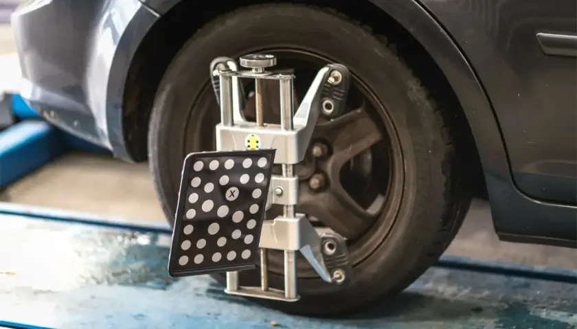 Réglage du parallélisme des roues d'une voiture avec un appareil de mesure. Le montage pneu et parallélisme est essentiel pour une conduite sûre.