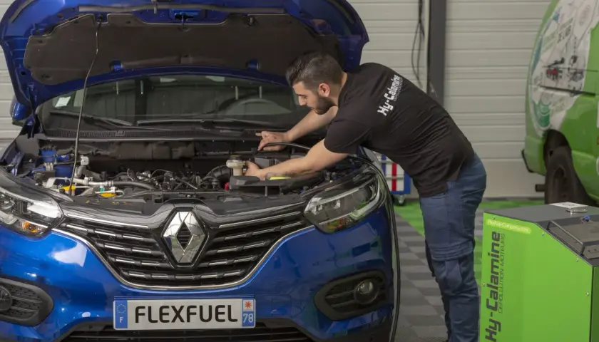 Mécanicien effectuant un décalaminage moteur essence. Avis positifs sur cette méthode de dépollution.