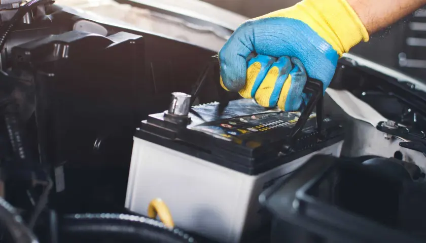 Main tenant une batterie de voiture, prêt à la changer.