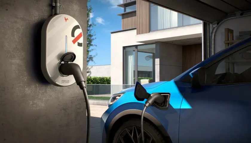 Borne de recharge électrique connectée à une voiture bleue devant une maison moderne. Idéal pour savoir où recharger voiture électrique.