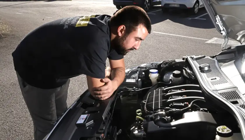Un mécanicien examine un moteur de voiture, soucieux du risque de casse moteur.