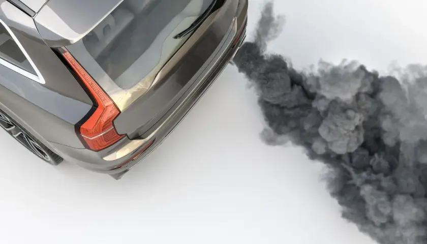 Vue aérienne d'un SUV gris émettant une épaisse fumée noire d'échappement, symbolisant la pollution.