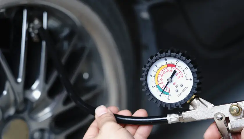 Main tenant vérifie la pression du pneu de voiture avec un manomètre. Il est prêt à gonfler le pneu.