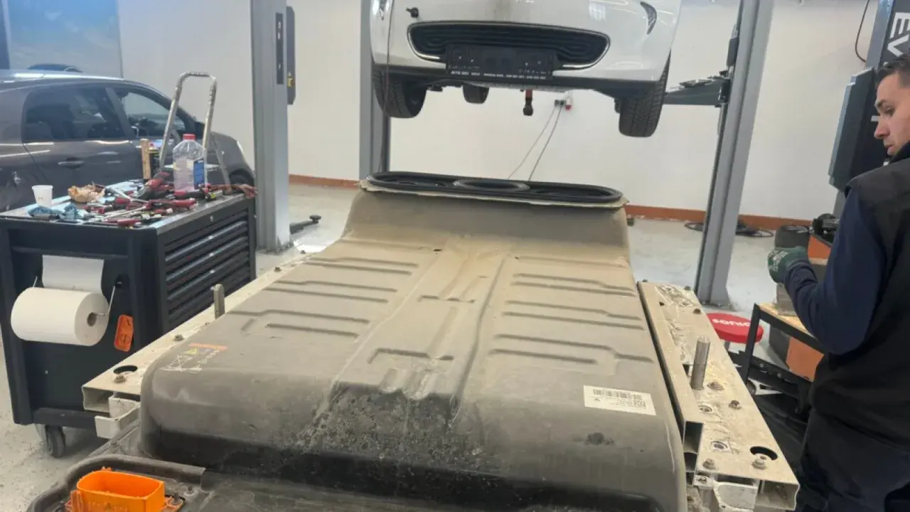 Un mécanicien travaille sur une batterie de voiture électrique, peut-être pour un changement de batterie chez Renault.