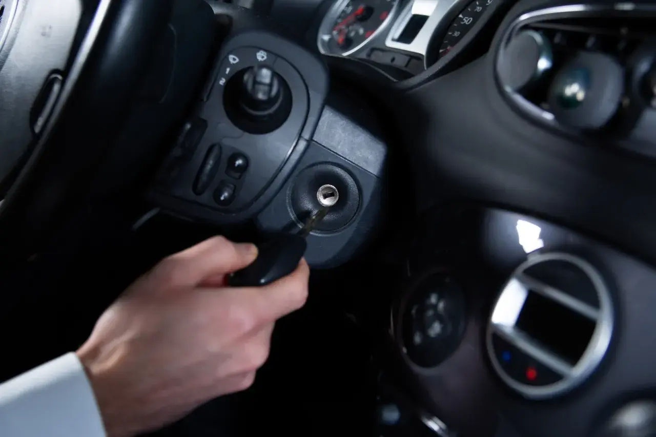 Main d'homme insérant une clé dans le Neiman d'une voiture. Le prix du changement de Neiman est une préoccupation courante.