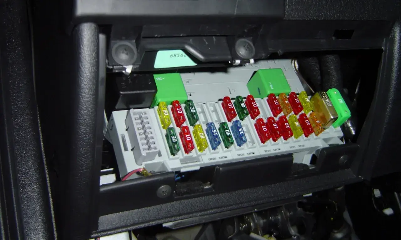 Boîte de fusibles de voiture avec des fusibles colorés de différentes ampérages. Un fusible de 20A est visible.