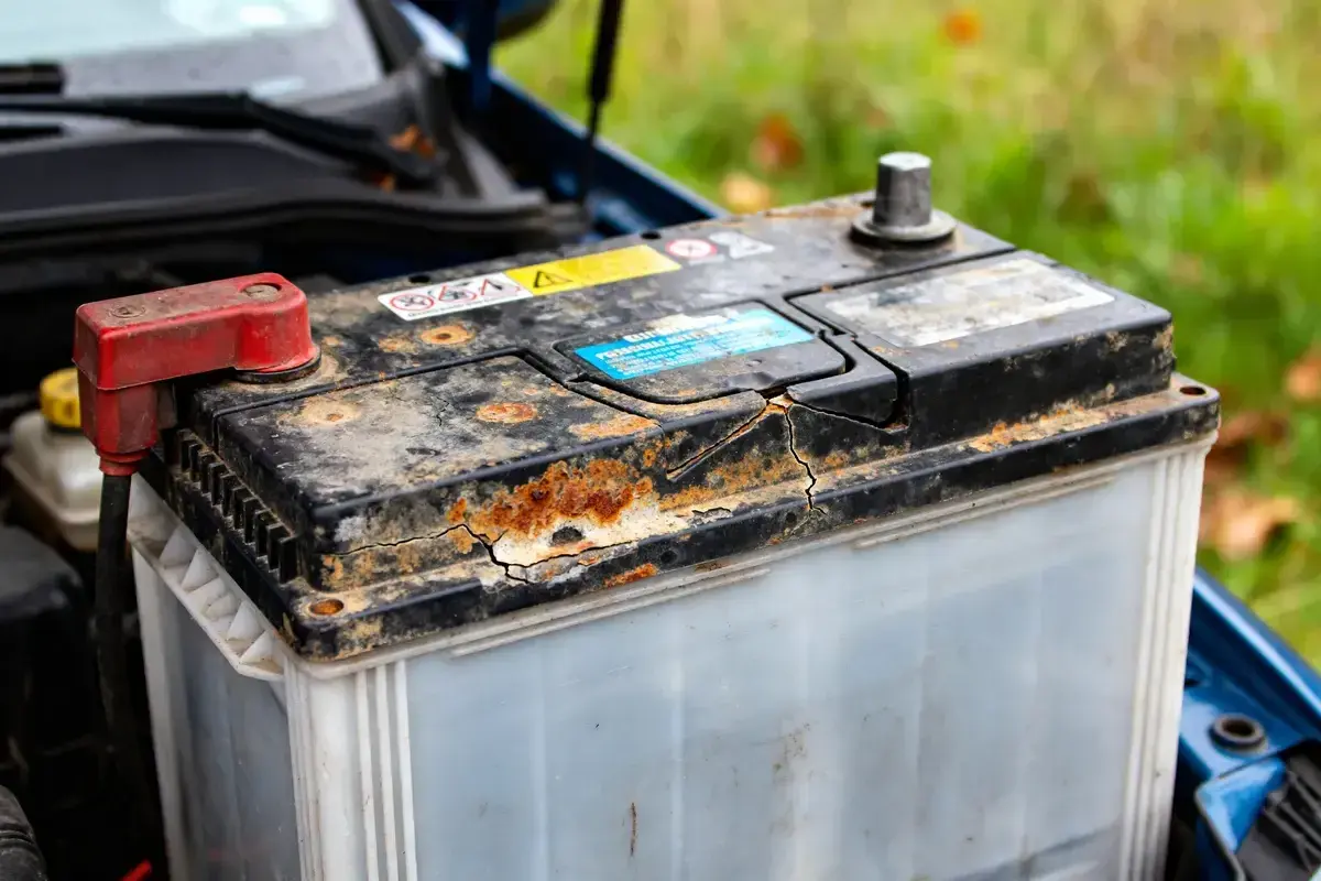 Batterie de voiture rouillée et fissurée, signe d'une durée de vie batterie voiture réduite.