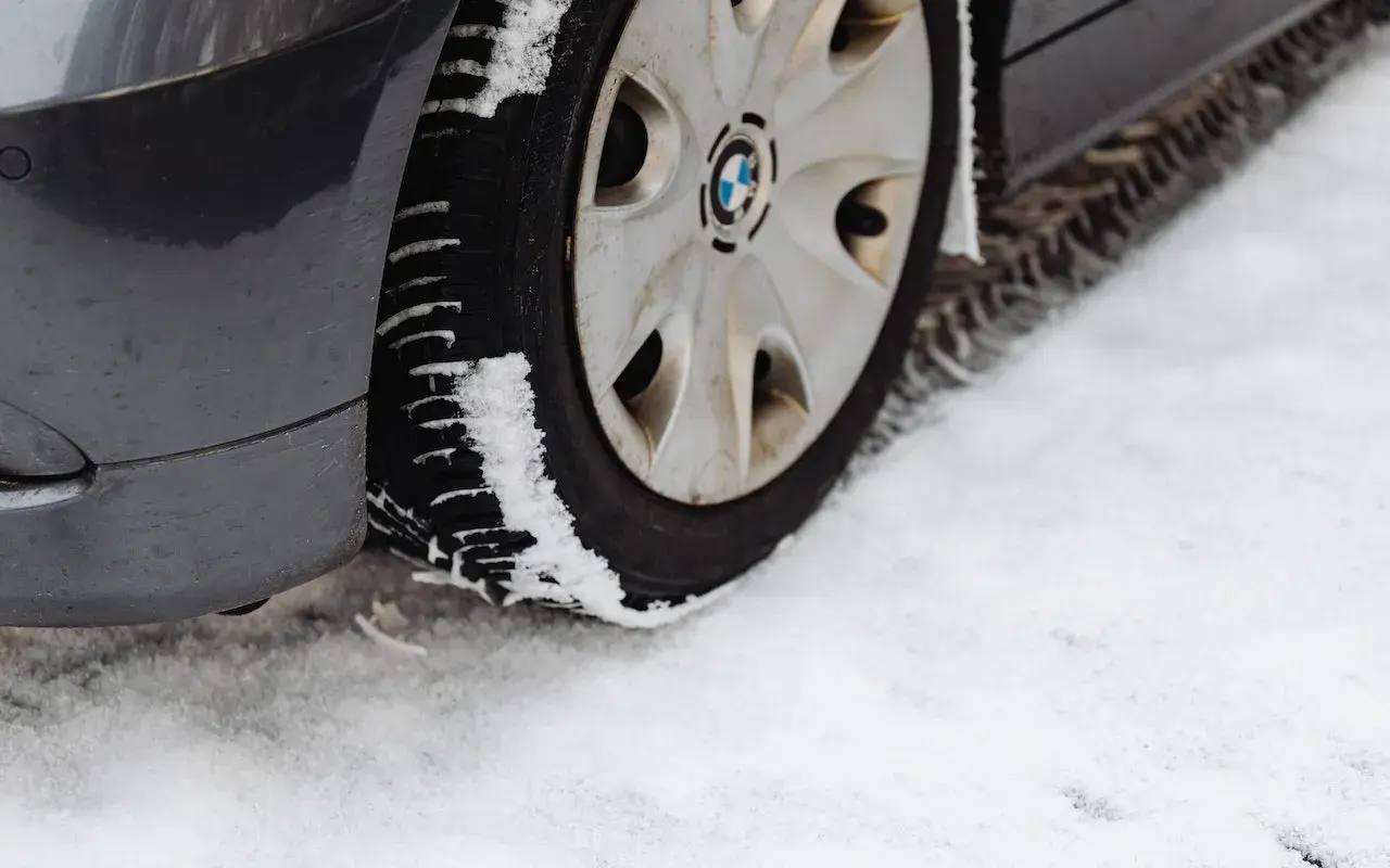 Pneu de voiture sur la neige. La neige s'accumule sur le pneu, illustrant pourquoi les pneus 4 saisons sont à éviter en conditions hivernales extrêmes.