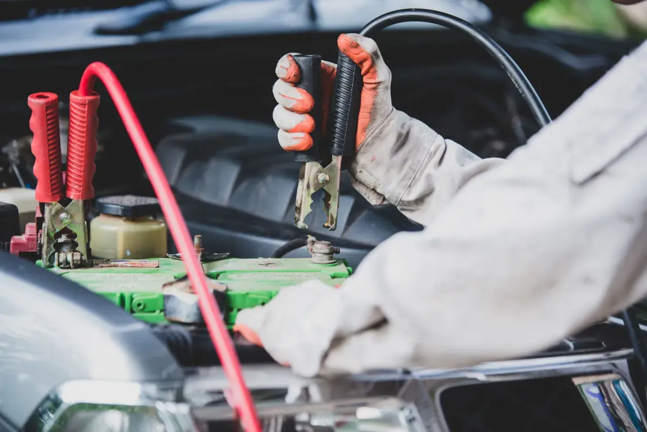 Mainteneur branchant des câbles sur la batterie pour démarrer une voiture qui ne démarre pas mais batterie ok.