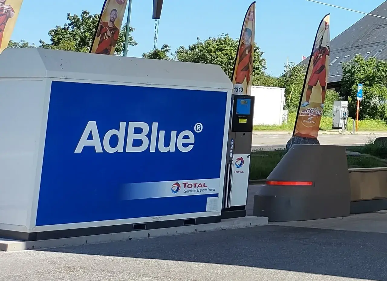 Station-service Total avec une pompe AdBlue à la vue. Des drapeaux aux couleurs nationales flottent au-dessus.