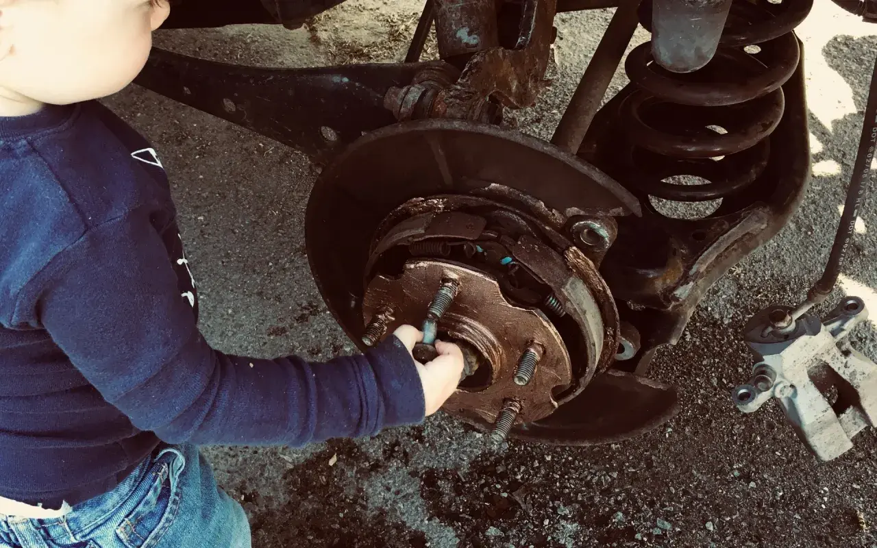 Un enfant touche le système de freinage d'une voiture. Un diagnostic freinage gratuit est peut-être en cours.