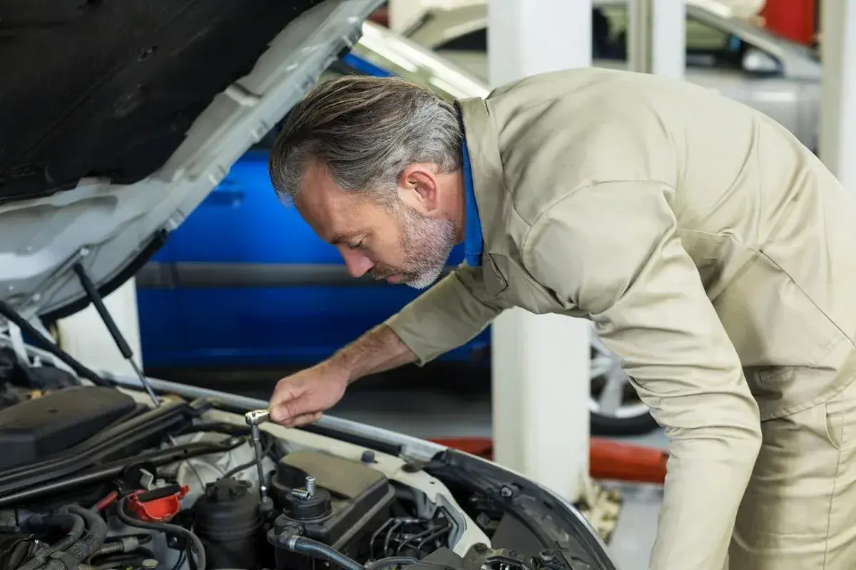 Mécanicien concentré sur le moteur, s'assurant de la pleine puissance moteur de la voiture.