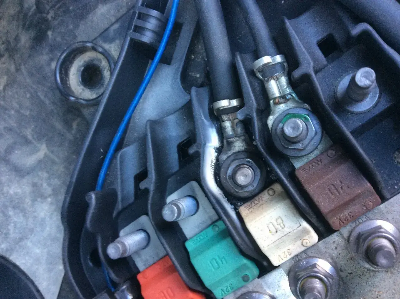 Boîtier de fusibles d'une Peugeot 207, incluant le fusible direction assistée. Connexions et câbles visibles.