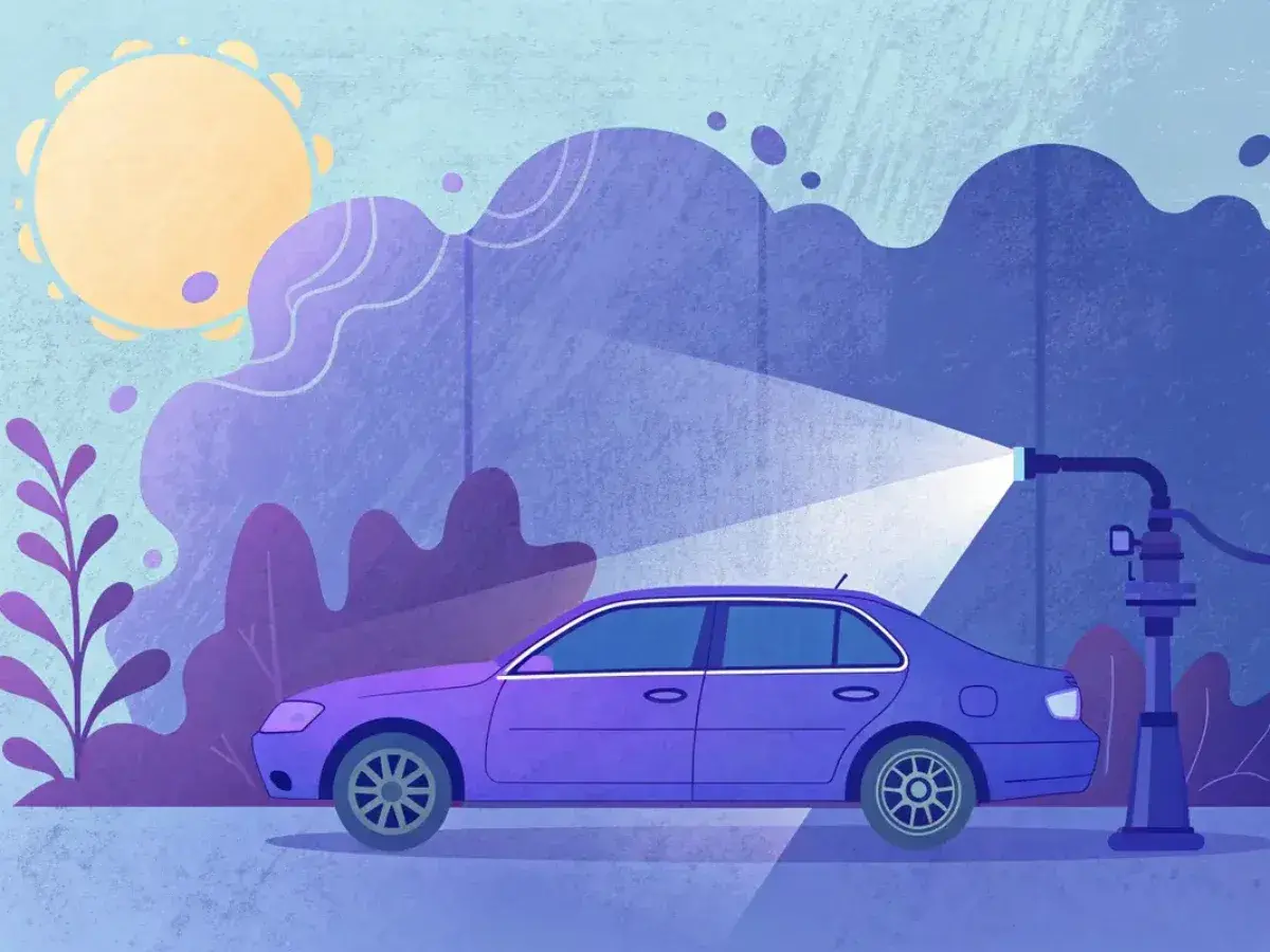 Une voiture violette est arrosée par un jet d'eau. Le soleil brille. Le tarif changement pompe à eau est peut-être abordé ici.