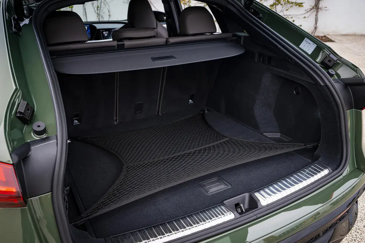 Coffre d'Audi Q5 vert, avec filet de rangement. L'emplacement de la batterie est discret sous le plancher.