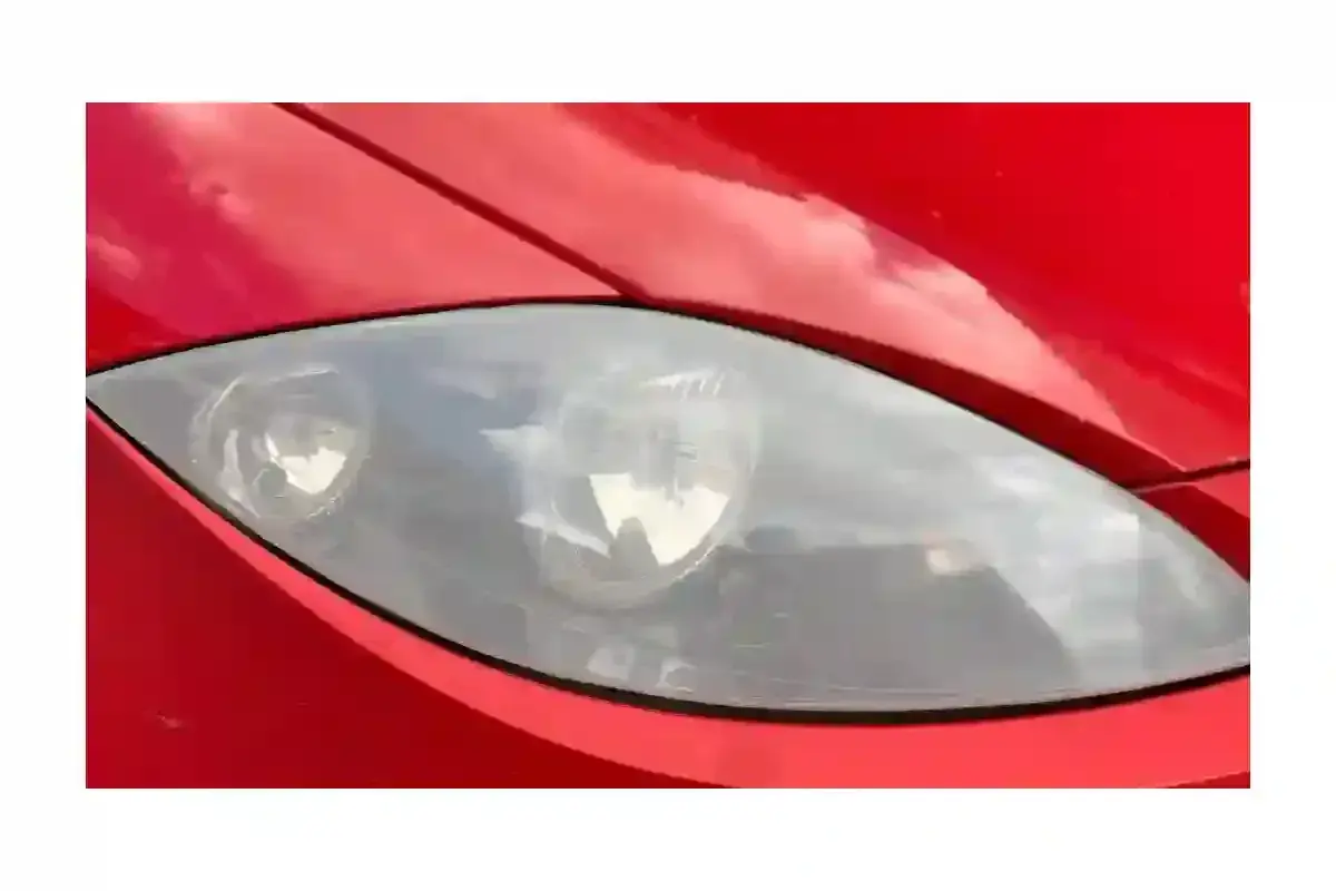 Phare de voiture rouge terni, prêt pour un nettoyage efficace avec du vinaigre blanc.