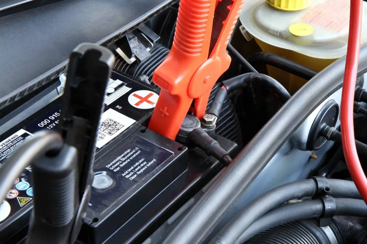 Pinces rouges connectées à la batterie pour recharger batterie voiture. Le niveau d'acide est indiqué.