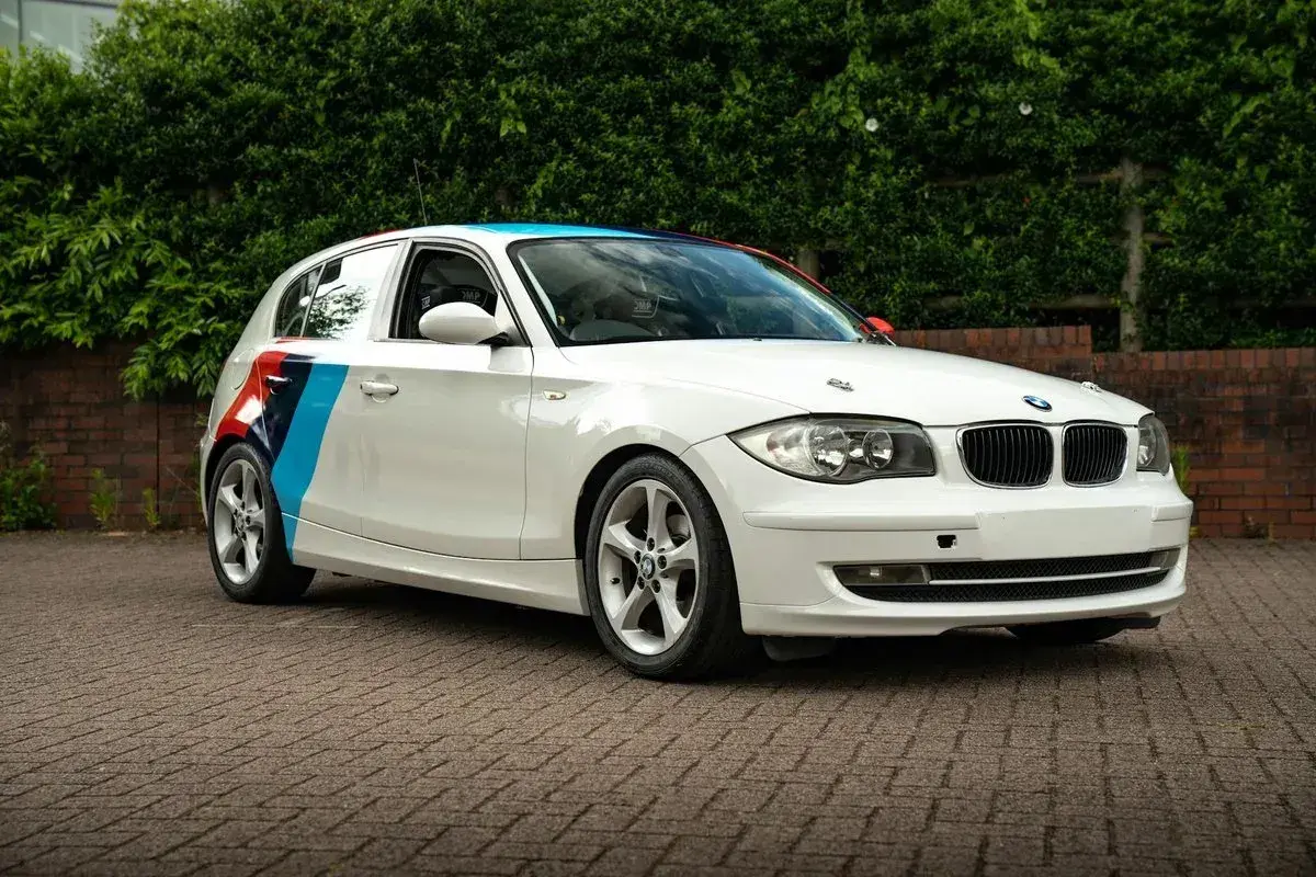 BMW blanc avec bandes tricolores sur le flanc, prêt pour son entretien.