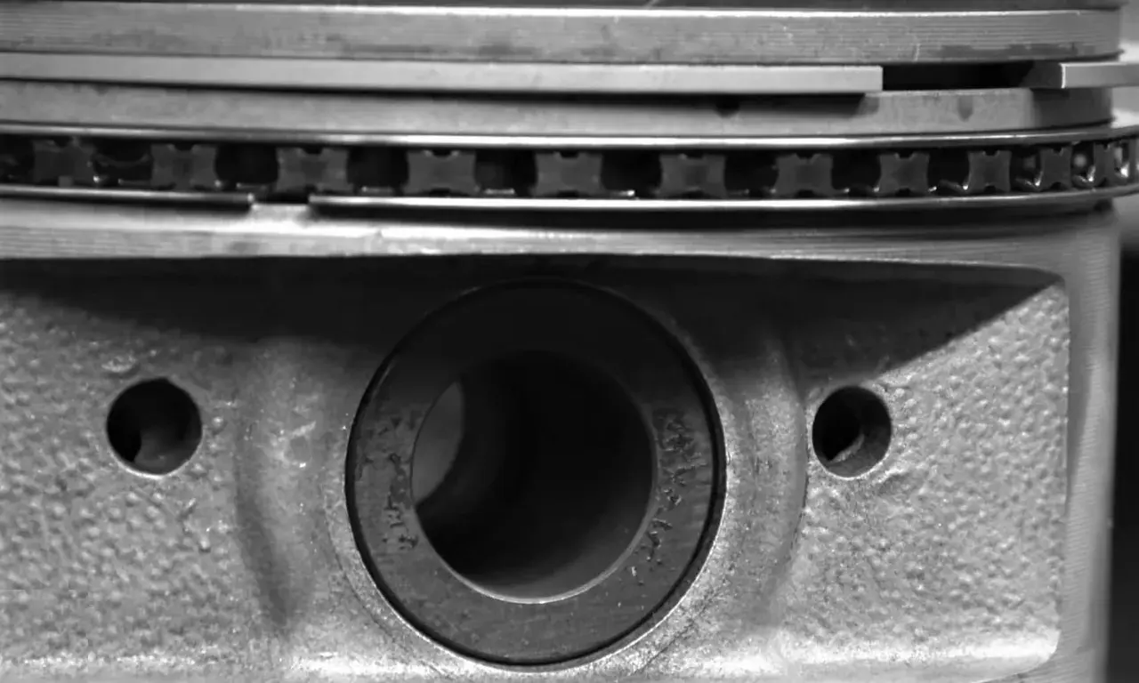 Gros plan sur un piston de moteur, montrant les segments et le logement de l'axe. La segmentation moteur est essentielle pour l'étanchéité.