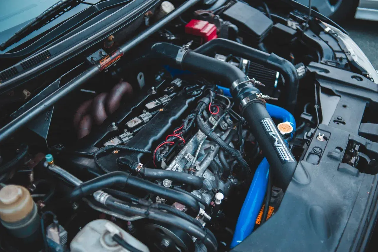 Moteur de voiture avec durites bleues et noires. Un symptôme capteur pression admission HS peut être lié à ces composants.