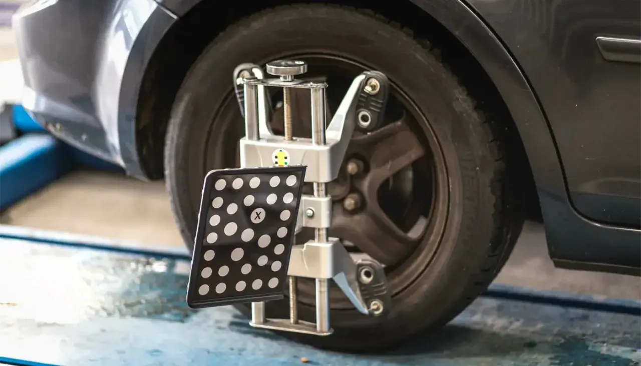 Réglage du parallélisme des roues d'une voiture avec un appareil de mesure. Le montage pneu et parallélisme est essentiel pour une conduite sûre.