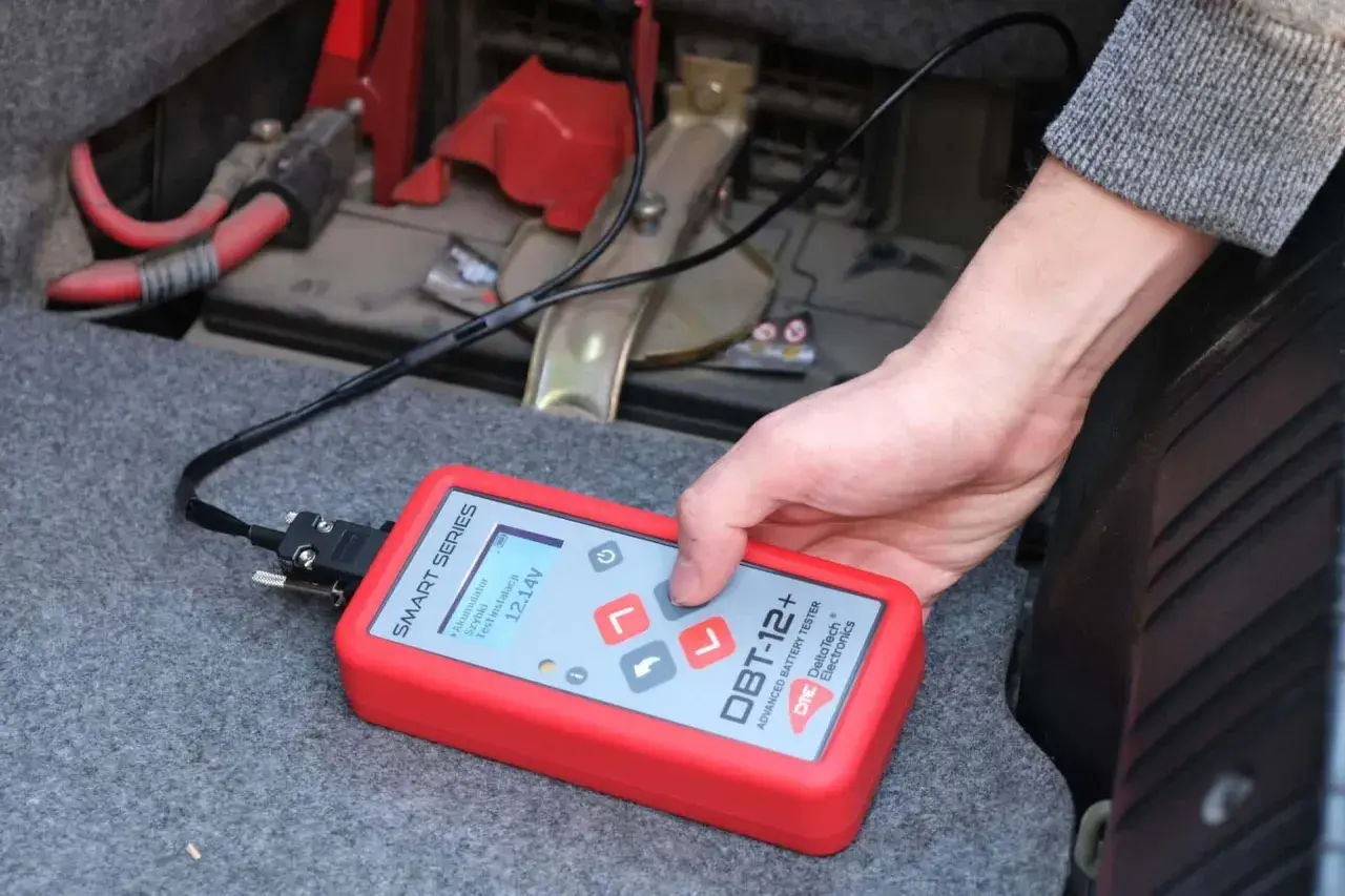 Utilisation d'un testeur de batterie avancé pour savoir comment tester une batterie sans multimètre. L'appareil affiche 12.14V.