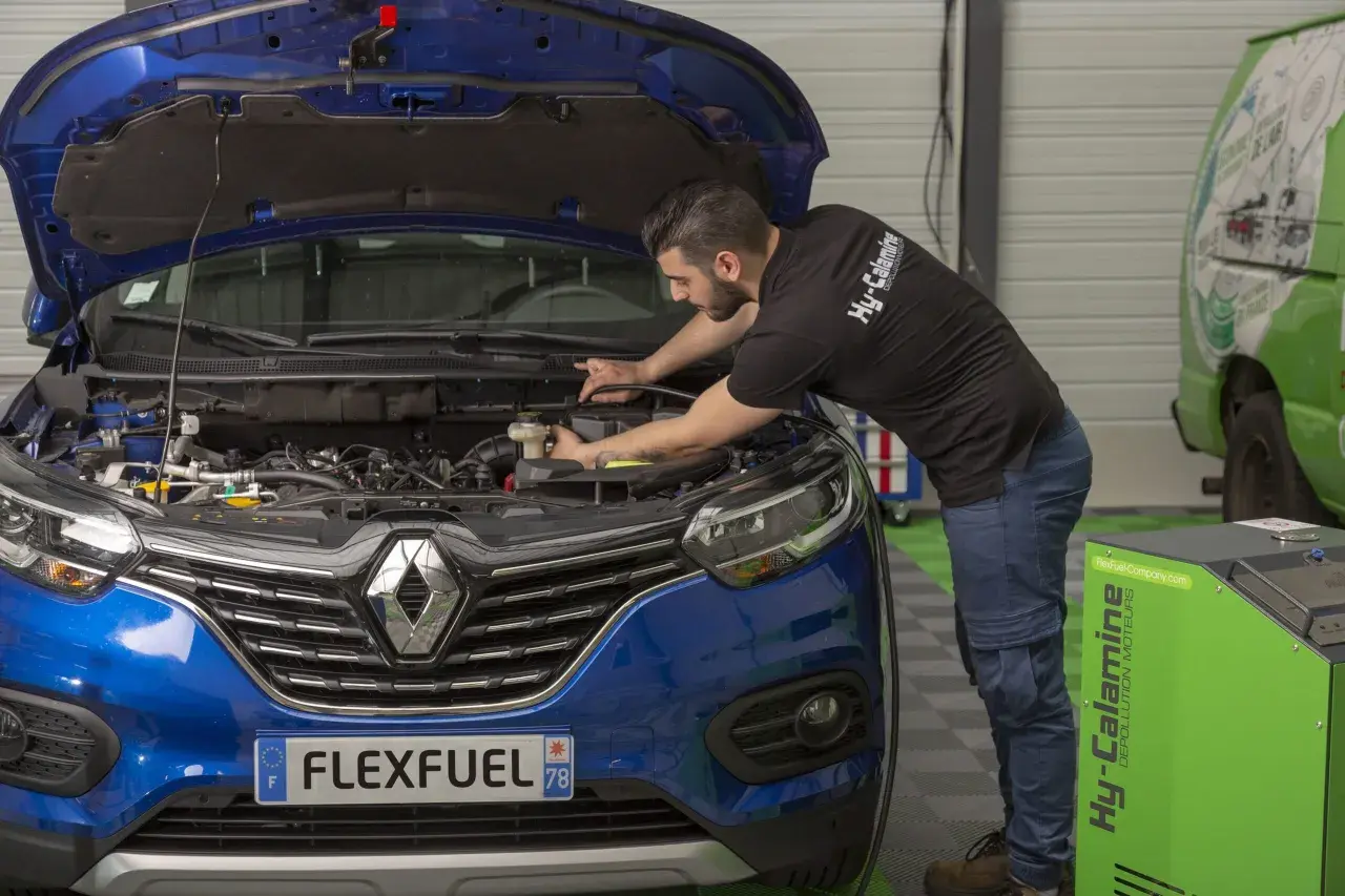Mécanicien effectuant un décalaminage moteur essence. Avis positifs sur cette méthode de dépollution.