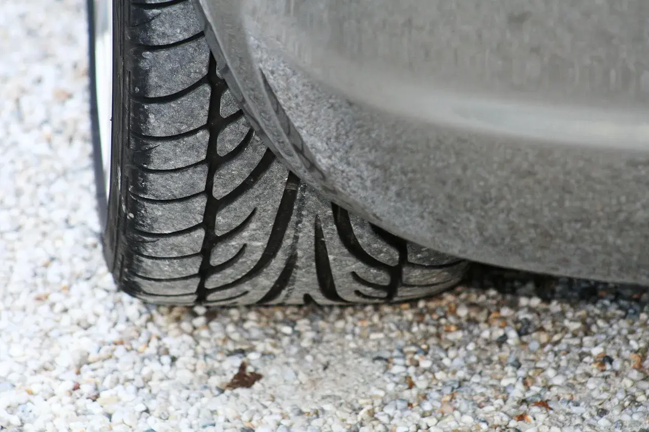 Gros plan sur un pneu de voiture usé, posé sur des graviers. J'espère que mes pneus font du bruit quand je roule, car ils sont en fin de vie !