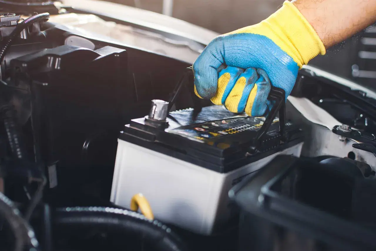 Main tenant une batterie de voiture, prêt à la changer.